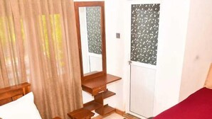 A bedroom with a wooden bed, a desk, a chair, a mirror, and a wardrobe. - Harambathenna Resort Anuradhapura (Anuradhapura)