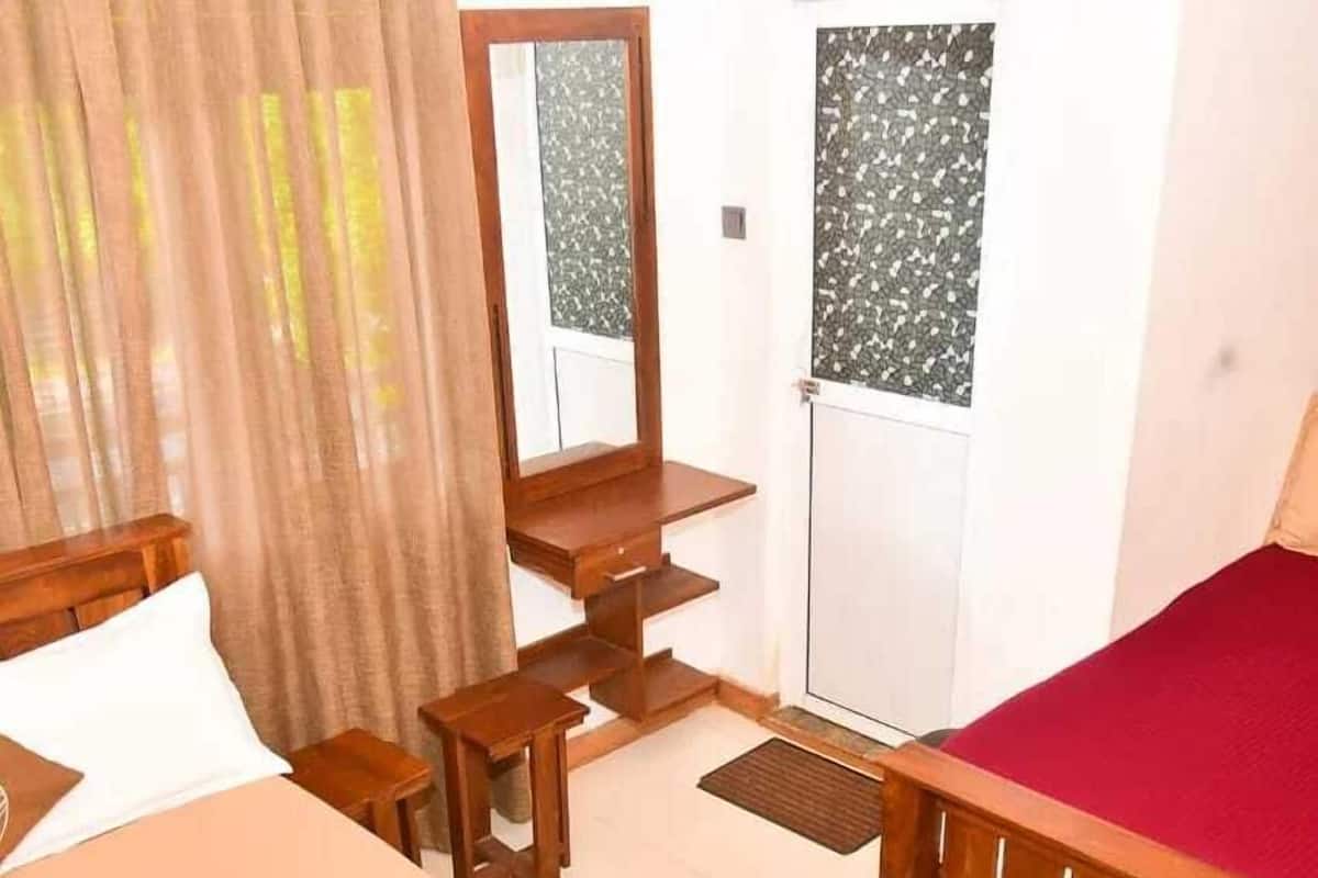 A bedroom with a wooden bed, a desk, a chair, a mirror, and a wardrobe.