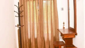 A room with a wooden desk, a chair, a coat rack, and a mirror. - Harambathenna Resort Anuradhapura (Anuradhapura)
