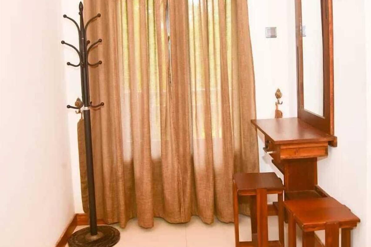 A room with a wooden desk, a chair, a coat rack, and a mirror.