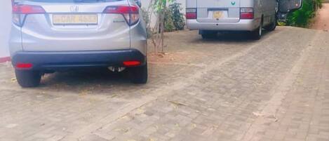 A paved driveway with a parked car and a bus.