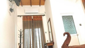 A bedroom with a wooden bed, a mirror, a window with a mosaic design, and an air conditioning unit. - Harambathenna Resort Anuradhapura (Anuradhapura)