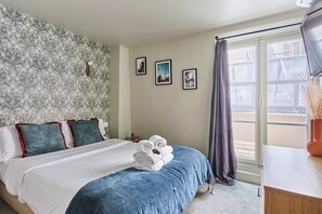 A bedroom with a bed, a nightstand, and a window with a view of buildings. - Charming Studio Center of Paris (Paris)