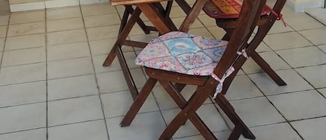 Un comedor con mesa y sillas de madera, un banco acolchado y piso de baldosas.