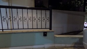 Ein gefliester Außenbereich mit Metallgeländer und einer kleinen Mauer.