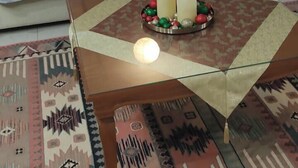 Ein Wohnzimmer mit einer Couch, einem Couchtisch mit Kerzen und Dekoration, einem gemusterten Teppich und Holzkredenz in der Ferne.