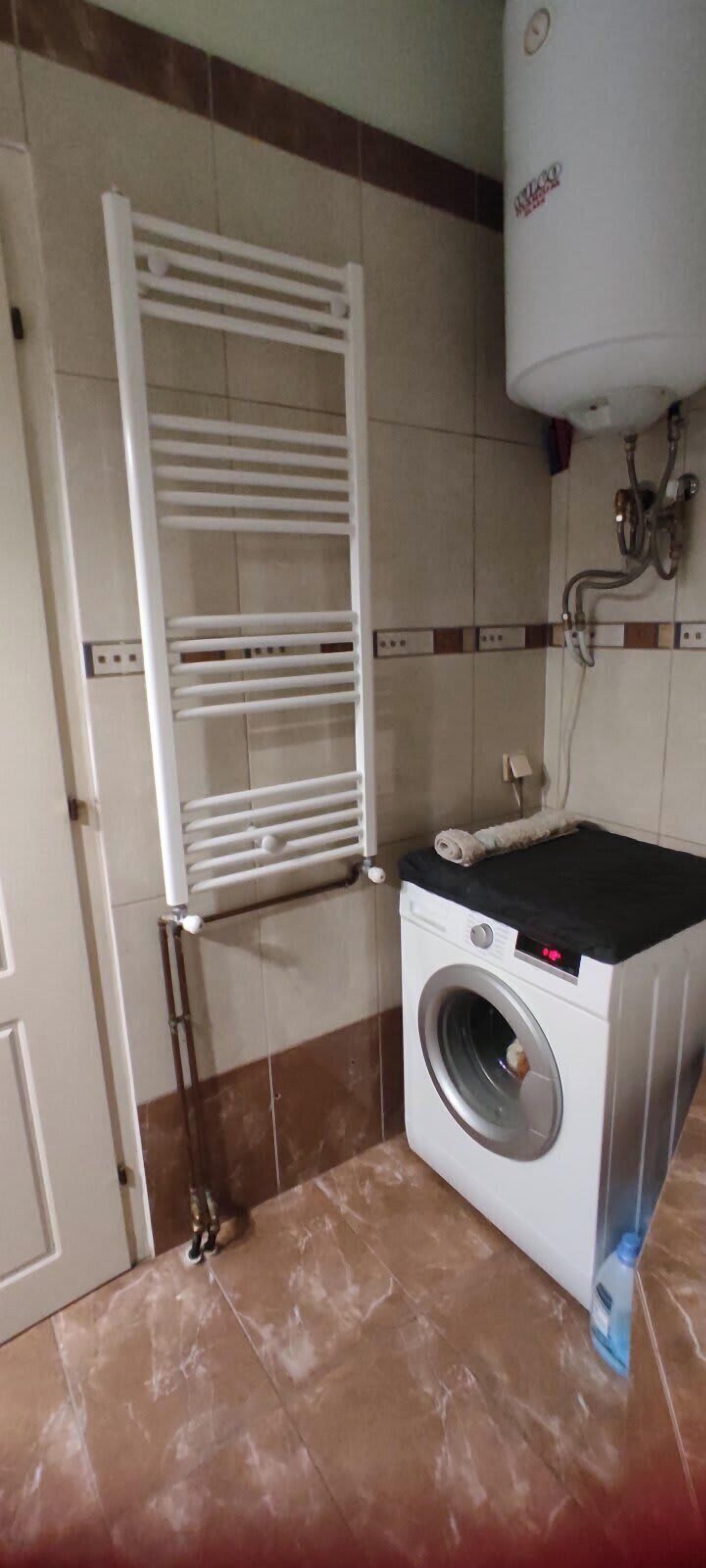 A laundry area with a washing machine, a drying rack, and a water heater.