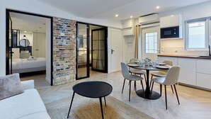 A modern living space with a dining area, kitchen, and a bedroom with a sliding glass door. - Superb Apartment Arc de Triomphe (Paris)