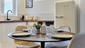 A dining area with a round table set for four, a white refrigerator, and a window with a view of buildings. - Superb Apartment Arc de Triomphe (Paris)
