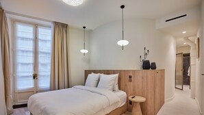 A modern bedroom with a large bed, a bedside table, and a built-in bench. - Studio Louvre Museum Palais-royal (Paris)