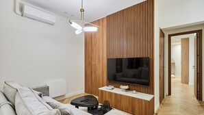 Una sala de estar moderna con un televisor de pantalla plana, un sofá, una mesita de centro y una pared de acento de madera.