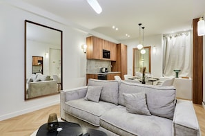 Un soggiorno moderno con un divano grigio, mobili contenitori in legno e una zona pranzo con tavolo e sedie.