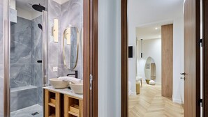 Un baño moderno con ducha de mármol, tocador de madera y un espejo grande.