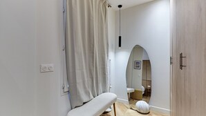 Un baño con cortina de ducha, un banco, un espejo y suelo de madera.
