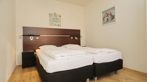 Una cama doble con cabecera de madera, dos mesitas de noche y un interruptor de luz.