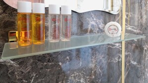 A bathroom shelf with four bottles of liquid soap and a soap dish.