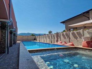 Una piscina con un muro de piedra y vistas a montañas al fondo.