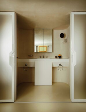 A bathroom with a double sink, a mirror, and a towel rack.