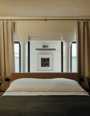 A hotel room with a bed, a framed picture on the wall, and a window with curtains.