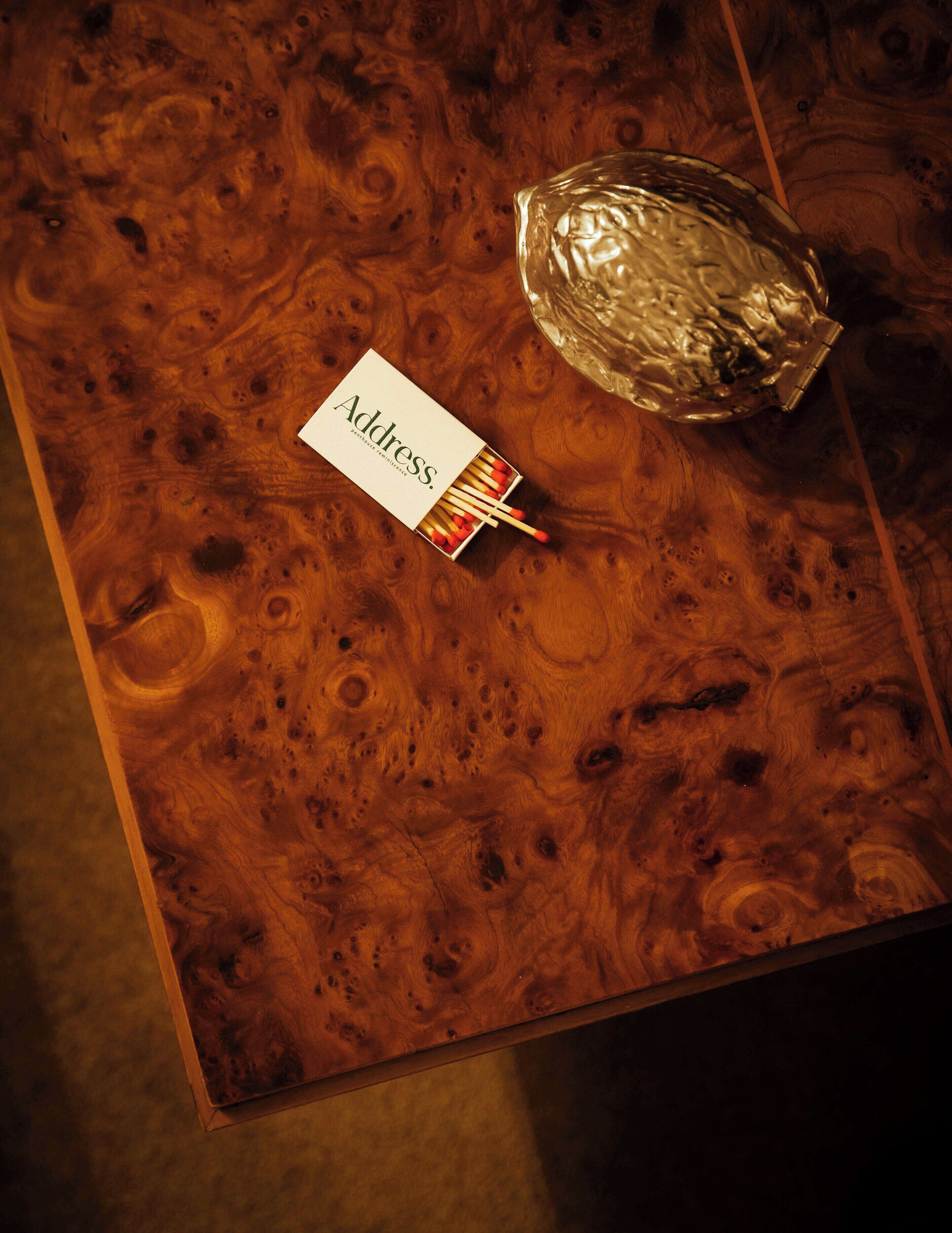 A wooden table with a white box labeled "Address" and a matchbox.