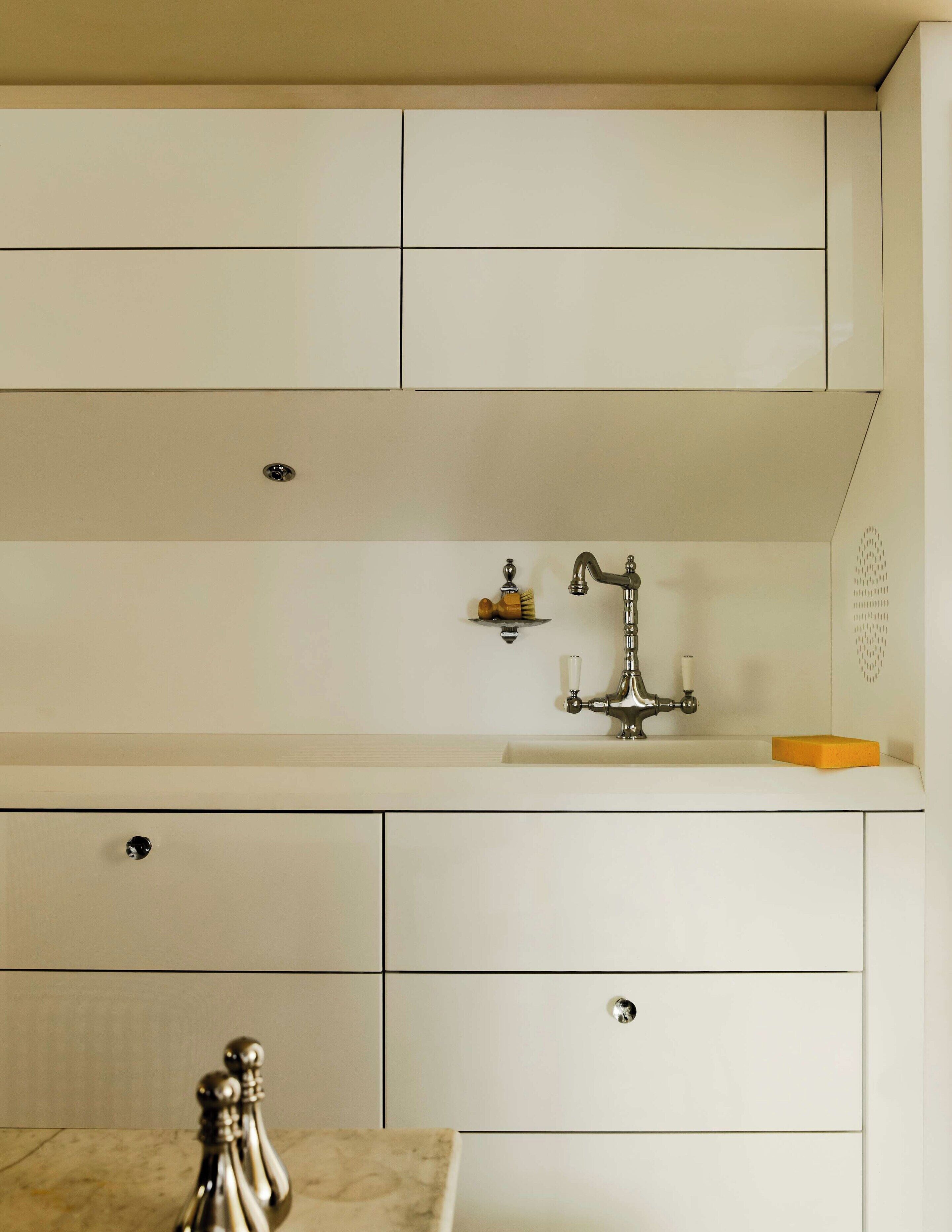 A kitchen with white cabinets, a stainless steel sink, and a marble countertop.