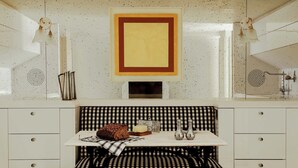 A kitchen with a checkered bench, two stools, a framed artwork, and a tiled backsplash. - Sublim and Design Apartement Place Vendome (Paris)