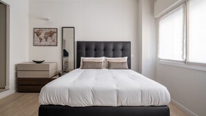 Un dormitorio moderno con una cama grande, un aparador, un espejo y un mapa del mundo en la pared.