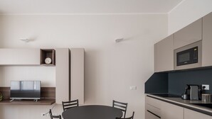 Una cocina moderna con microondas integrado, cafetera y televisor de pantalla plana.