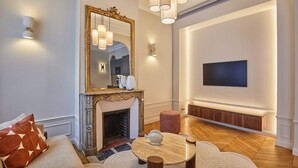 Una sala de estar moderna con chimenea, una mesa de centro redonda, un sofá y un televisor montado en la pared.