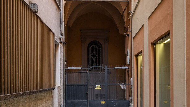 Un callejón con un arco de ladrillo que conduce a una entrada con portón.