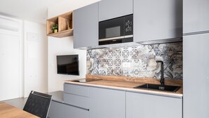 Una cocina moderna con armarios grises, encimera de madera, microondas negro y salpicadero de azulejos.
