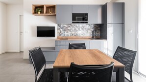 Una cocina moderna con armarios grises, una mesa de comedor de madera y sillas negras.