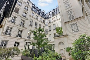 Un patio central con un árbol rodeado de edificios con balcones y molduras decorativas.