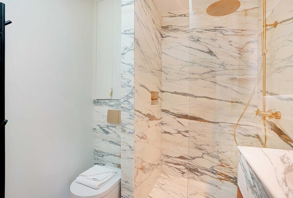 A bathroom with a marble shower wall, a toilet, and a sink. - Elegant Studio - 2P - Rue Saint-honore (Paris)