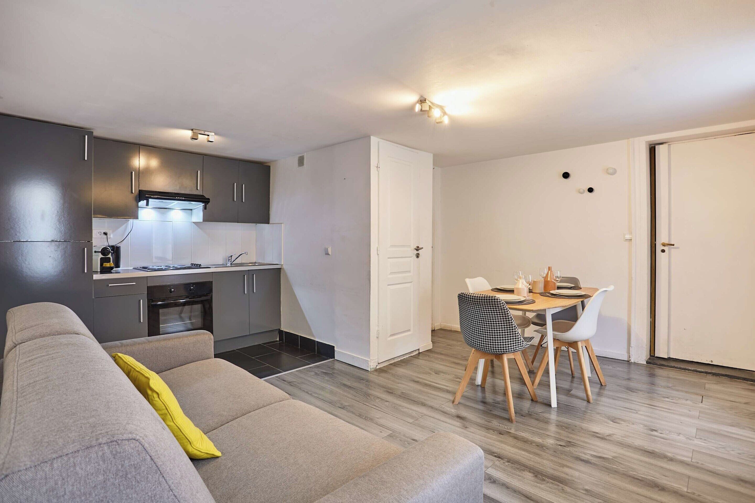 A compact living space with a kitchenette, a dining area, and a sofa.