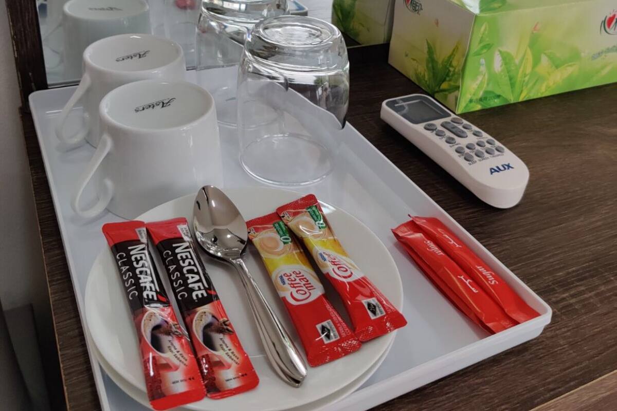 A breakfast tray with Nescafe Classic coffee, a spoon, a remote control, and a tissue box.