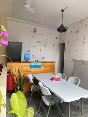 A hotel reception area with a wooden counter, a blue sign, and a white table with chairs. - Maavaharu K.Himmafushi  (Himmafushi)