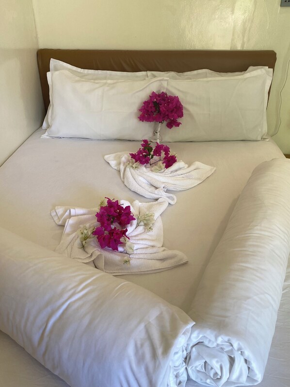 A neatly made bed with white linens and decorative towels arranged in a floral pattern. - Maavaharu K.Himmafushi (Himmafushi)