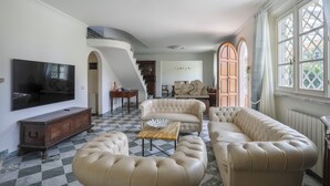 A spacious living room with a large television, a fireplace, and a staircase leading to another level.