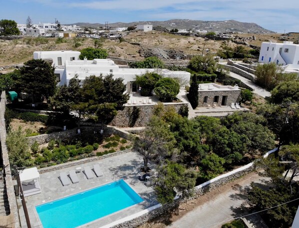 Stunning views of a serene Mediterranean-style property with a pool and lush surroundings.