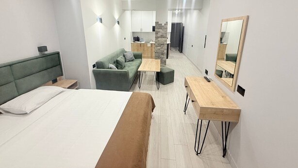 A modern hotel room with a bed, a sofa, a small table, and a mirror. - NineRooms Apart-Hotel (Yerevan)