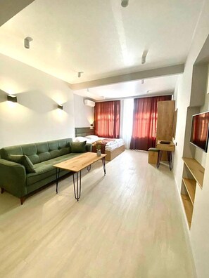 Ein modernes Wohnzimmer mit einem grünen Sofa, einem Holztisch und einem Bild an der Wand.