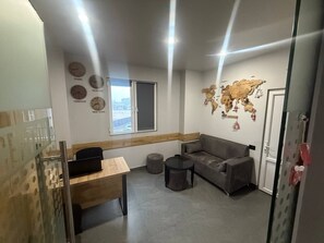 Ein moderner Arbeitsbereich mit Schreibtisch, grauem Sofa, rundem Tisch und einer Weltkarte an der Wand.