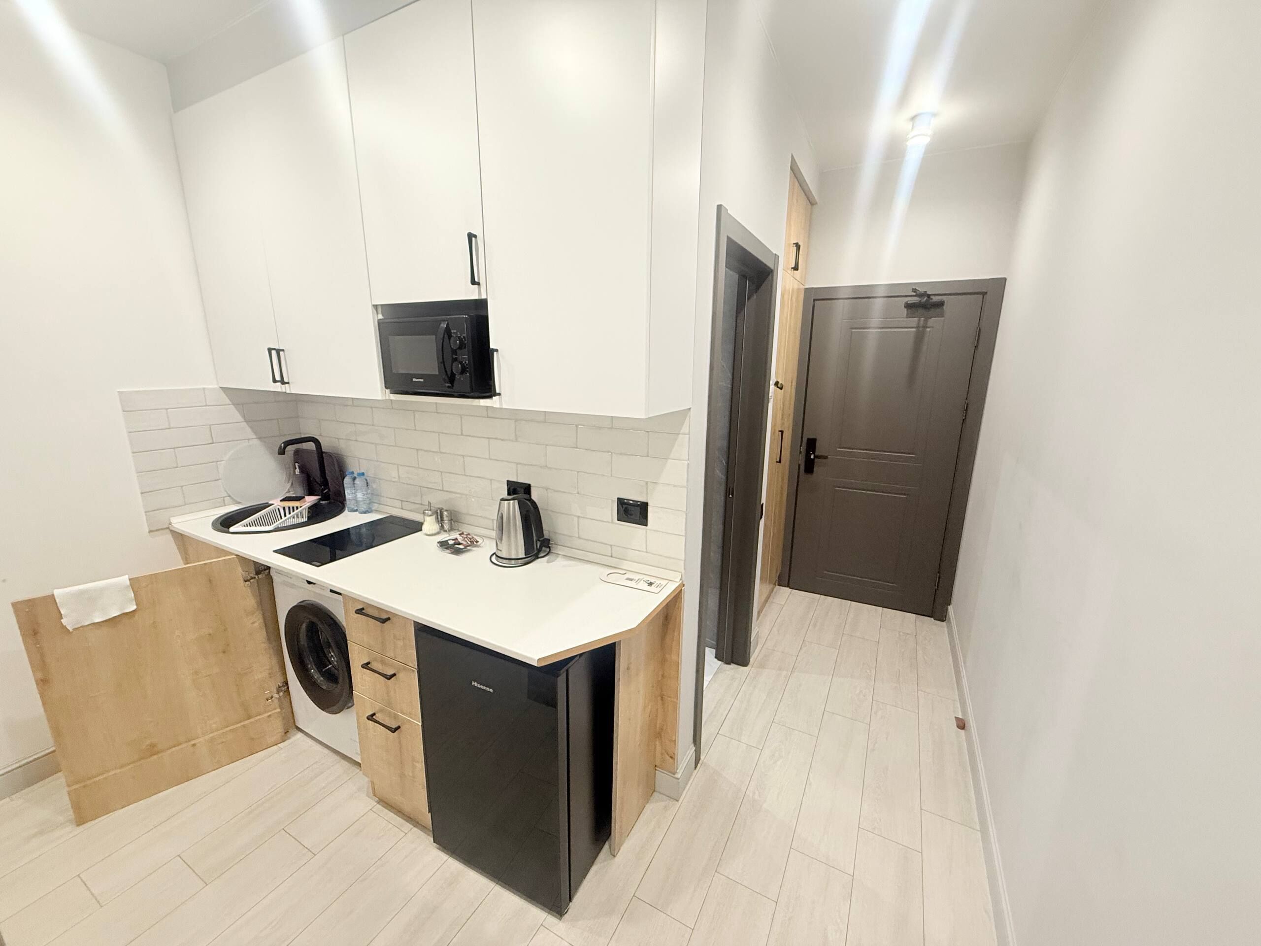 A compact kitchen with white cabinets, a black dishwasher, and a microwave.