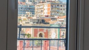 A view from a window of a building with multiple floors, balconies, and a red-tiled roof.