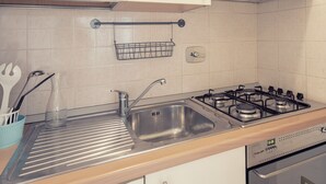 Cozinha moderna com armários brancos, eletrodomésticos de aço inoxidável e bancada de madeira.