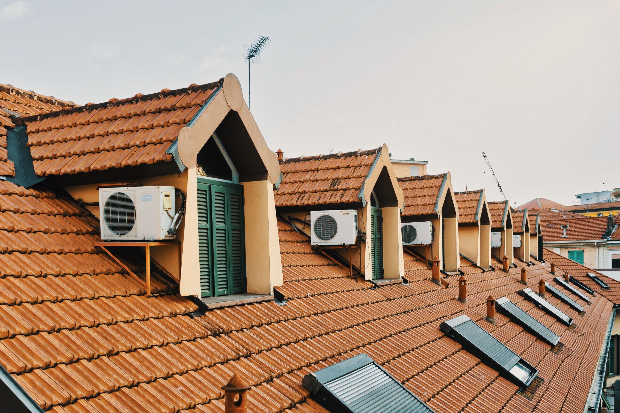 A row of buildings with sloped roofs and multiple air conditioning units installed.