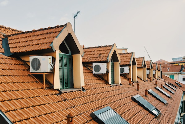 A row of buildings with sloped roofs and multiple air conditioning units installed.
