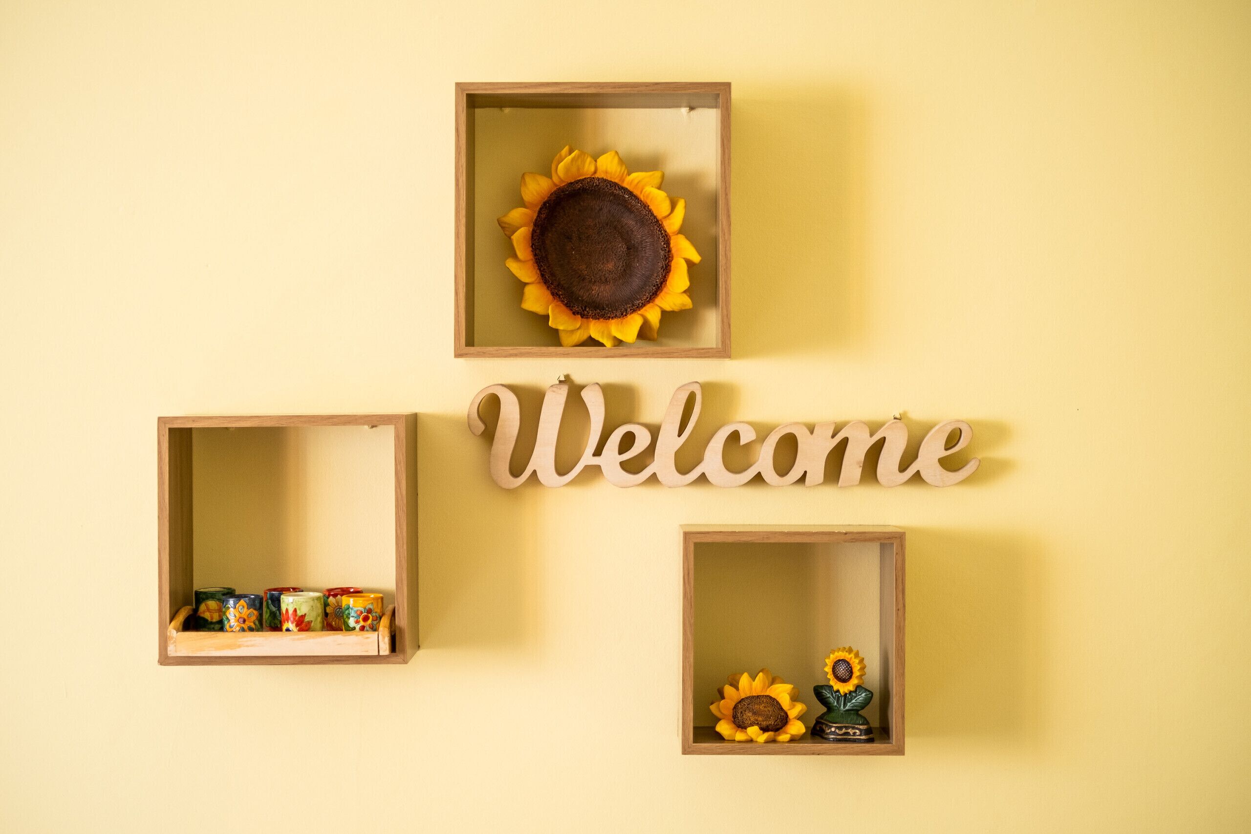 A wall with three wooden display cases and a 'Welcome' sign.
