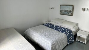 A small, clean room with a bed, a nightstand, and a painting on the wall.